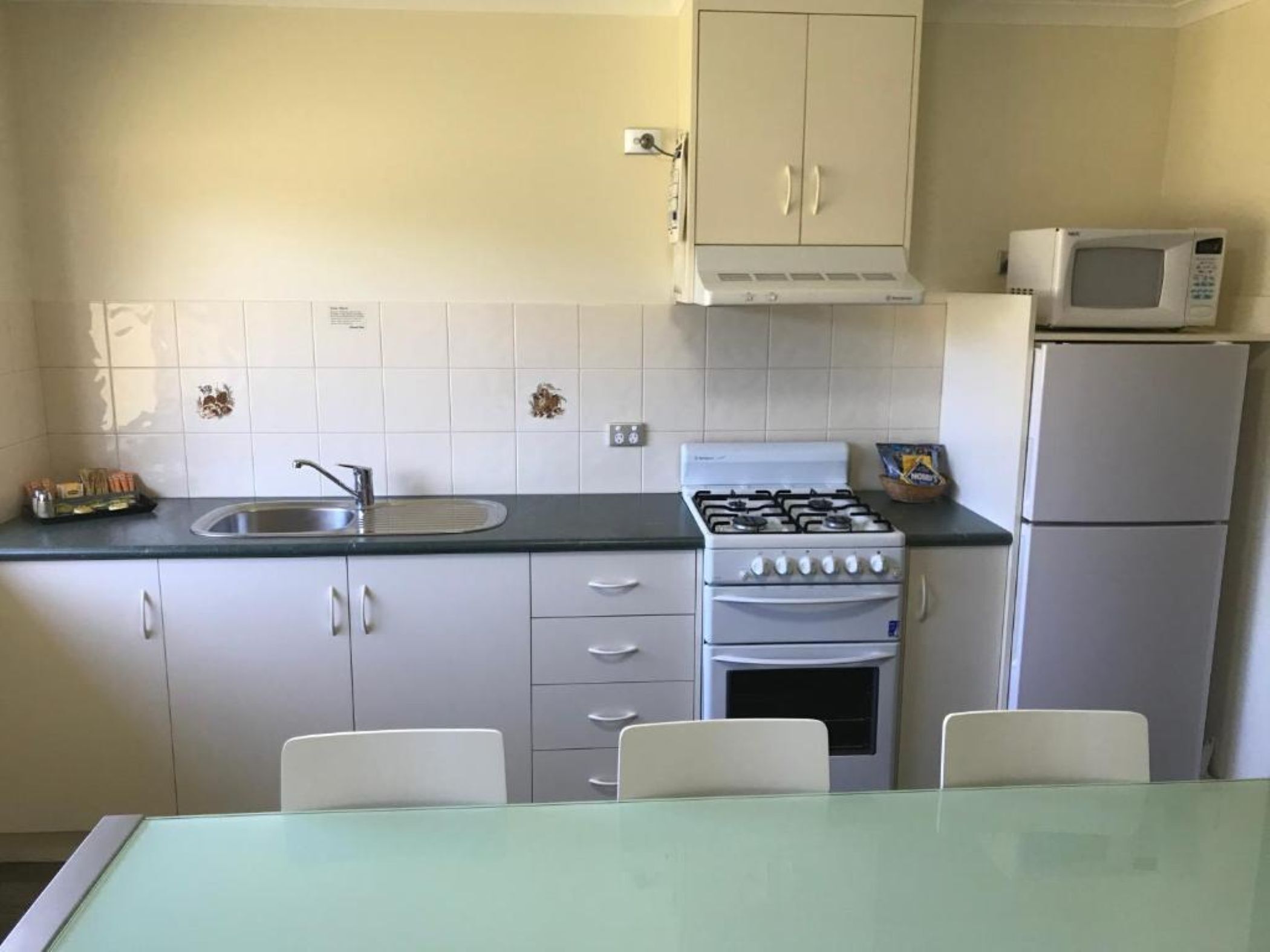 Cocina compacta con fregadero, estufa, microondas y refrigerador.