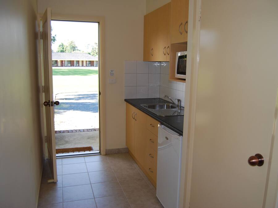 A kitchen with a microwave, sink, and cabinets.