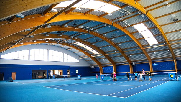 An indoor tennis court with a high ceiling and wooden beams. - Hotel Zawisza (Bydgoszcz)