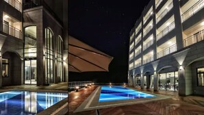 A modern hotel with a pool area, featuring a unique architectural design with arched structures and a large, illuminated pool. - Lapis Hotel (Namhae)