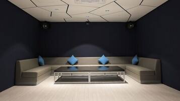 Una habitación moderna con sofá modular, una mesita de centro de vidrio y paredes oscuras.