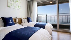 A hotel room with two beds, a large window with a view of the sea, and a balcony. - Lapis Hotel (Namhae)