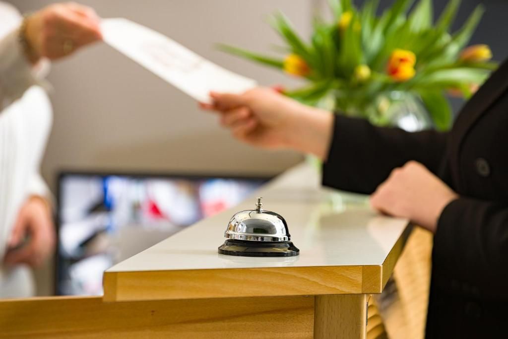Una recepción con un timbre, un monitor de computadora y una planta al fondo.