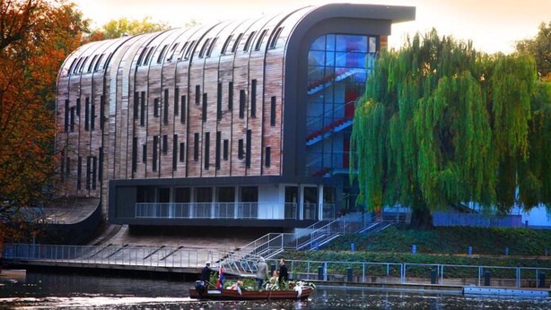 Un edificio moderno con fachada curva, amplios ventanales y vistas al agua.