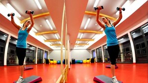 Un gimnasio con espejos, equipamiento de ejercicio y suelo rojo.