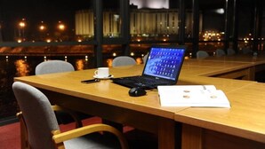 Una sala de conferencias con una computadora portátil, documentos y una taza sobre una mesa.