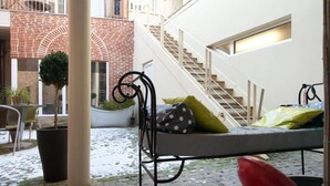 A courtyard with a staircase, a red chair, and a potted plant. - Hôtel le Prieuré (Amiens)