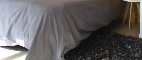 A bedroom with a bed, two wall-mounted lights, and a small table.