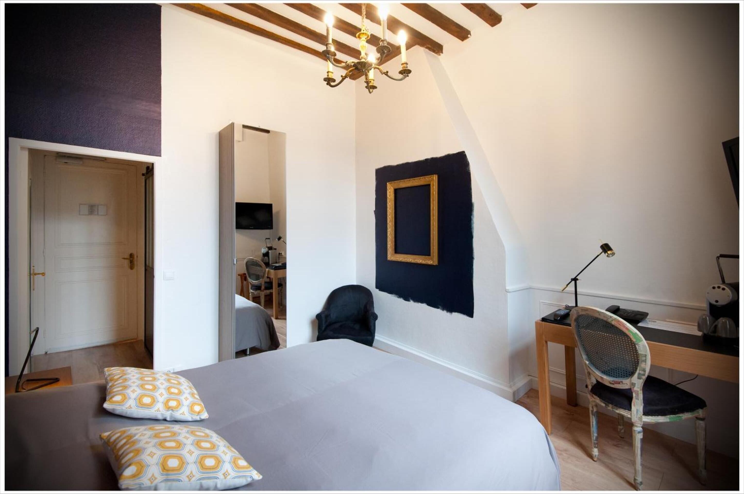 Une chambre à coucher comprenant un lit, un bureau, une chaise, un téléviseur et un lustre.