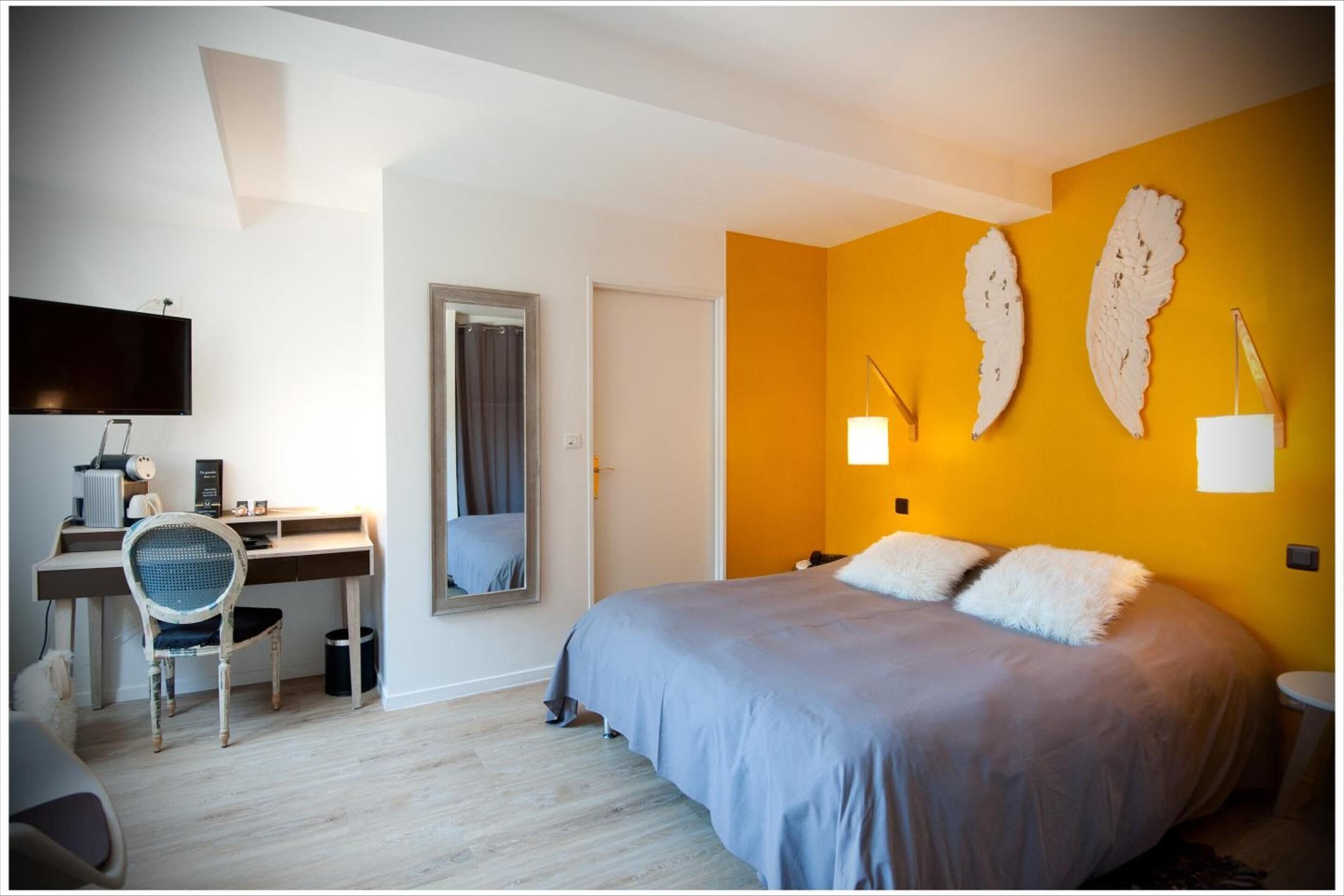 A bedroom with a bed, desk, chair, and a TV.