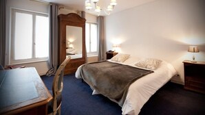 A hotel room with a bed, a desk, a chair, a mirror, and a chandelier. - La Résidence le Prieuré (Amiens)