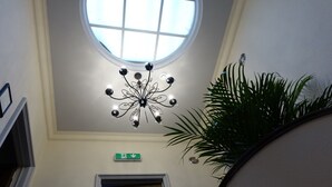 A hotel lobby with a modern chandelier, a large window, and a staircase. - J and R Brussels City Apartment (Brussels)