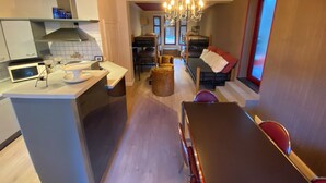 A modern kitchen with a microwave, a dining area with a table and chairs, and a living area with a sofa and ottoman. - J and R Brussels City Apartment (Brussels)