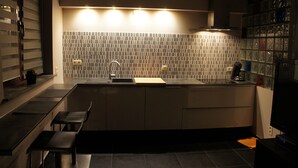 A modern kitchen with a tiled backsplash, a sink, and a countertop. There are cabinets and a chair. - J and R Brussels City Apartment (Brussels)