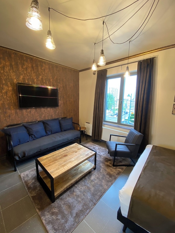 A modern living room with a sofa, a coffee table, a chair, and a TV mounted on the wall.