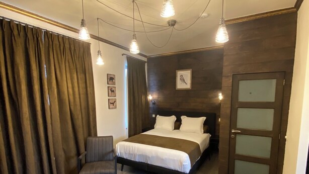 A modern bedroom with a large bed, a wooden coffee table, and a chair. - J and R Brussels City Apartment (Brussels)