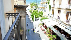 A narrow street with buildings on either side, outdoor seating for cafes, and pedestrians walking. - Sorrento Guest House (Sorrento)