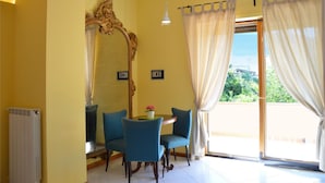 A room with yellow walls, a large mirror, a table with chairs, and a view through a glass door. - Sorrento Guest House (Sorrento)