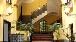 A grand staircase with a balustrade, surrounded by potted plants and illuminated by wall-mounted lamps. - Sorrento Guest House (Sorrento)