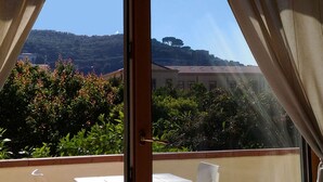 A balcony with a view of a hillside, a building, and a tree. - Sorrento Guest House (Sorrento)