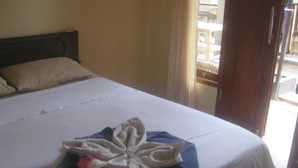 Een keurig opgemaakt bed met een gevouwen handdoek en een fles op het bed.