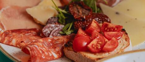 A plate of food with various meats, cheese, and tomatoes.