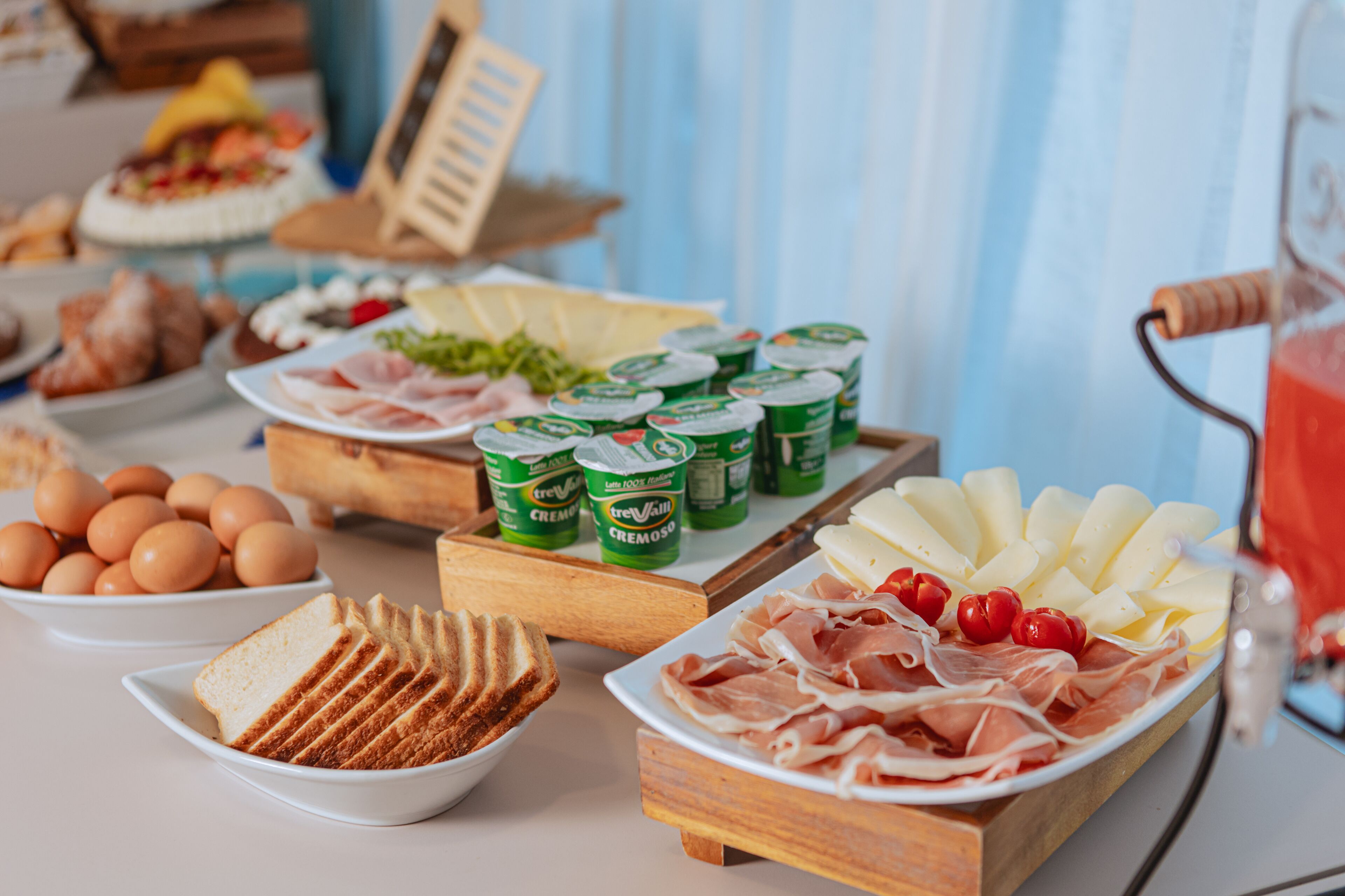 Un bufé con diversos alimentos, entre ellos pan, huevos, queso y carne.