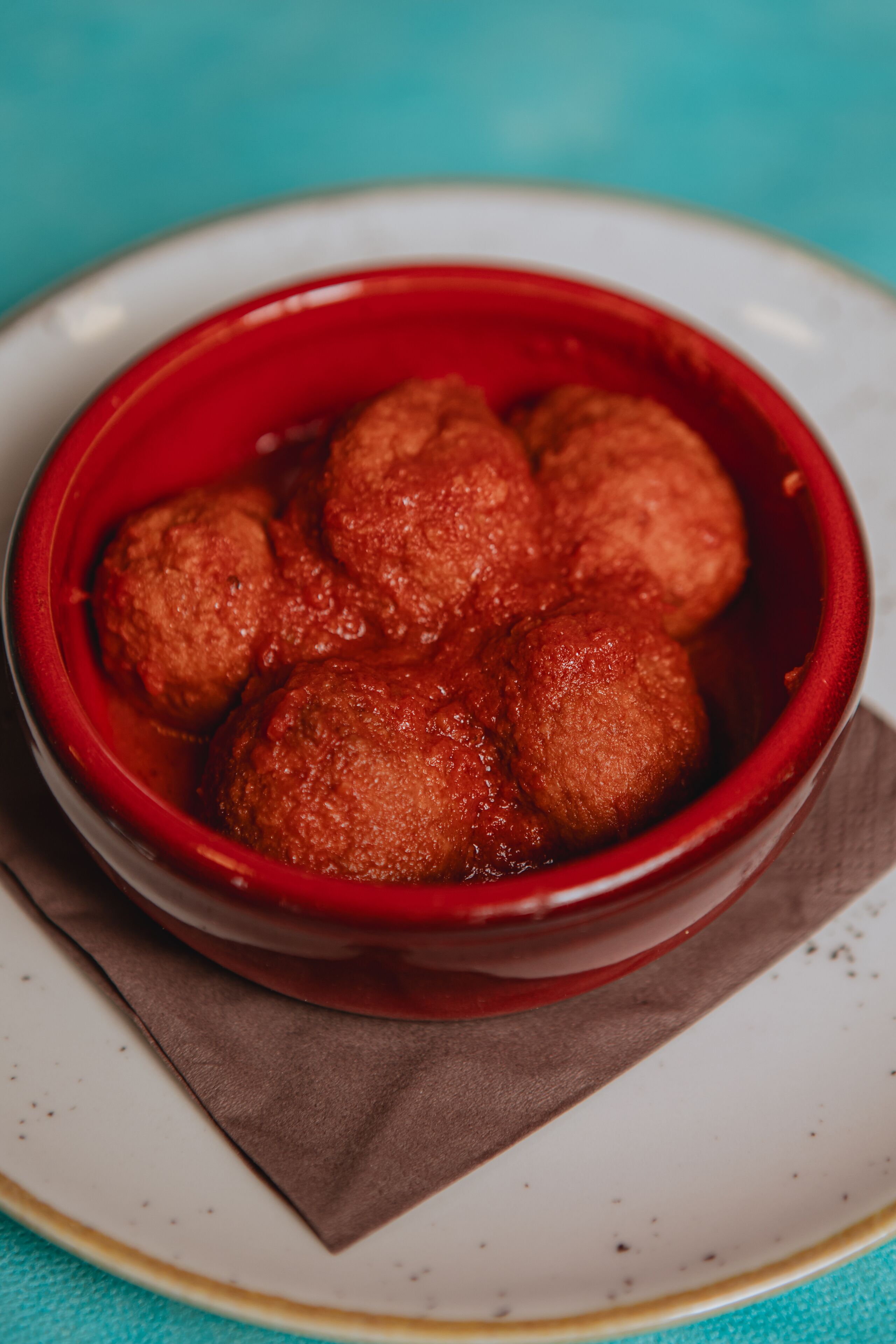 Un bol de boulettes de viande nappées de sauce tomate, servi sur une assiette.