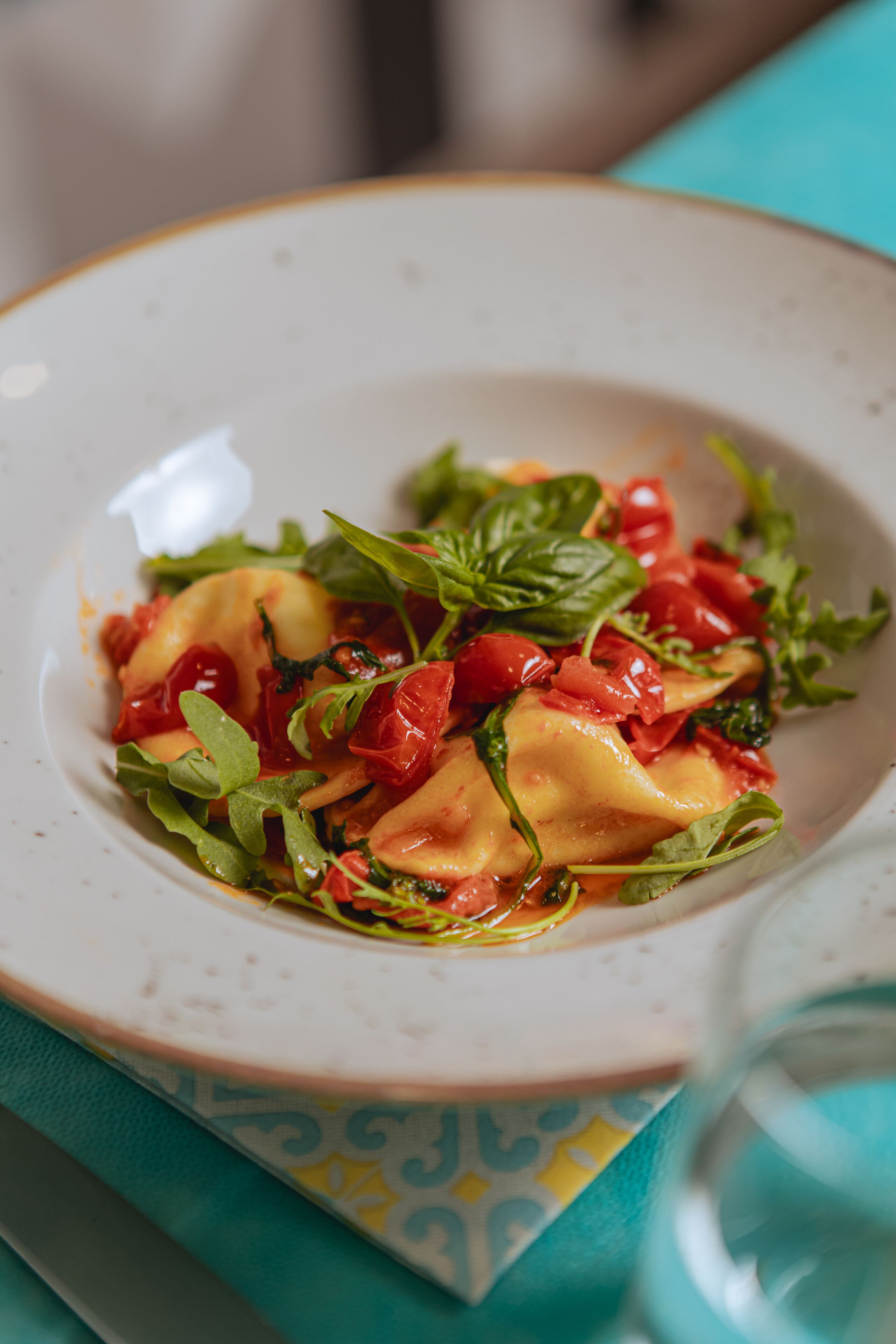 Ein Teller Ravioli mit Tomatensauce und Grünzeug.