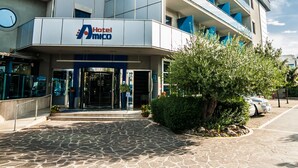 A modern hotel with a prominent logo, multiple balconies, and a stone-paved entrance. - Hotel Amico (Citta Sant'Angelo)