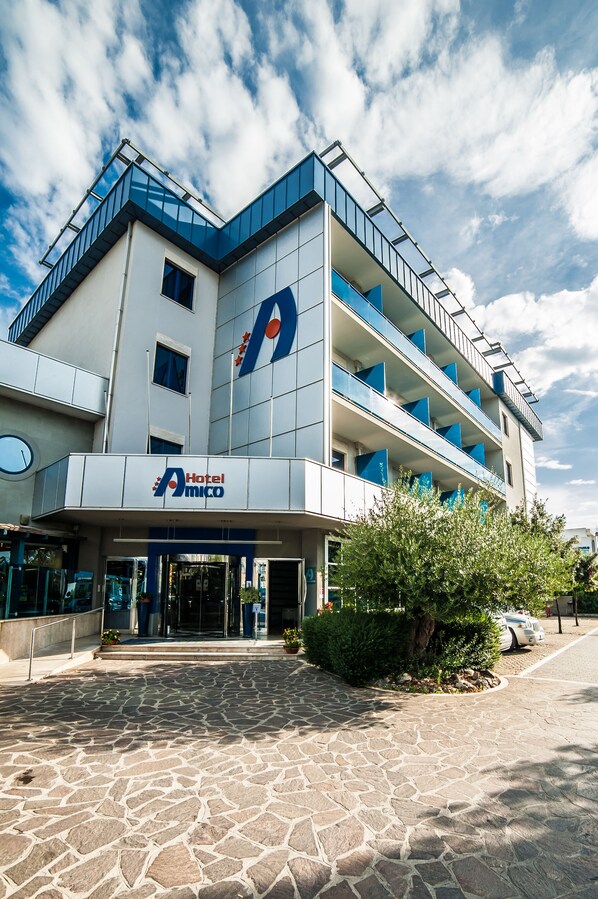 A modern hotel with a prominent logo, multiple balconies, and a stone-paved entrance. - Hotel Amico (Citta Sant'Angelo)