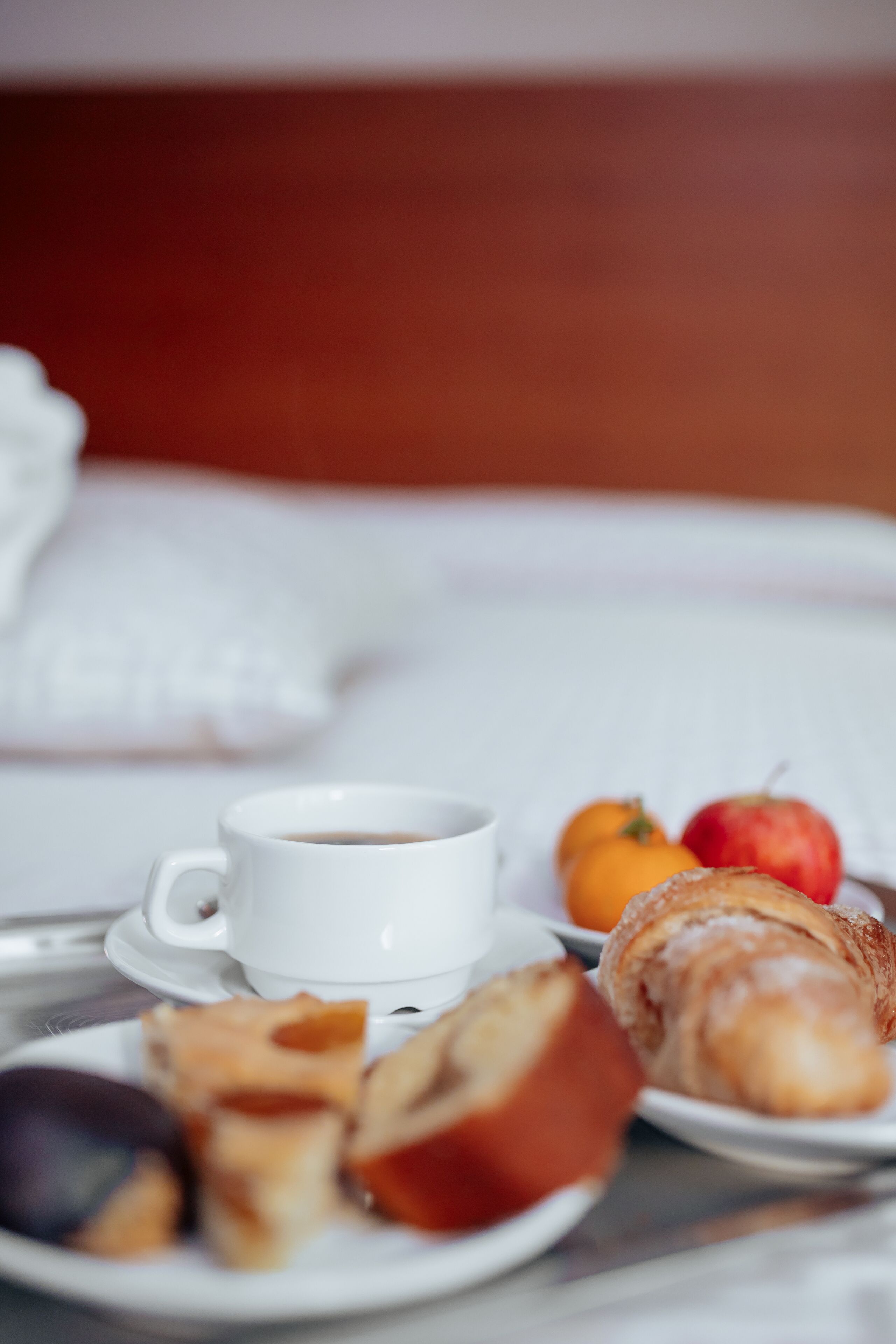 A breakfast setting with a cup of coffee, pastries, and fruits on a table.