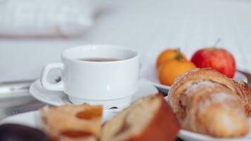 Une table dressée pour le petit-déjeuner, avec une tasse de café, des viennoiseries et des fruits.