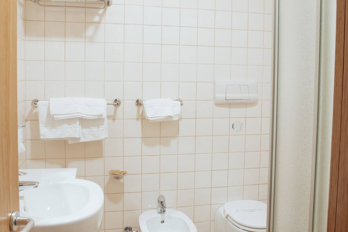 A bathroom with a sink, bidet, toilet, and towel racks.