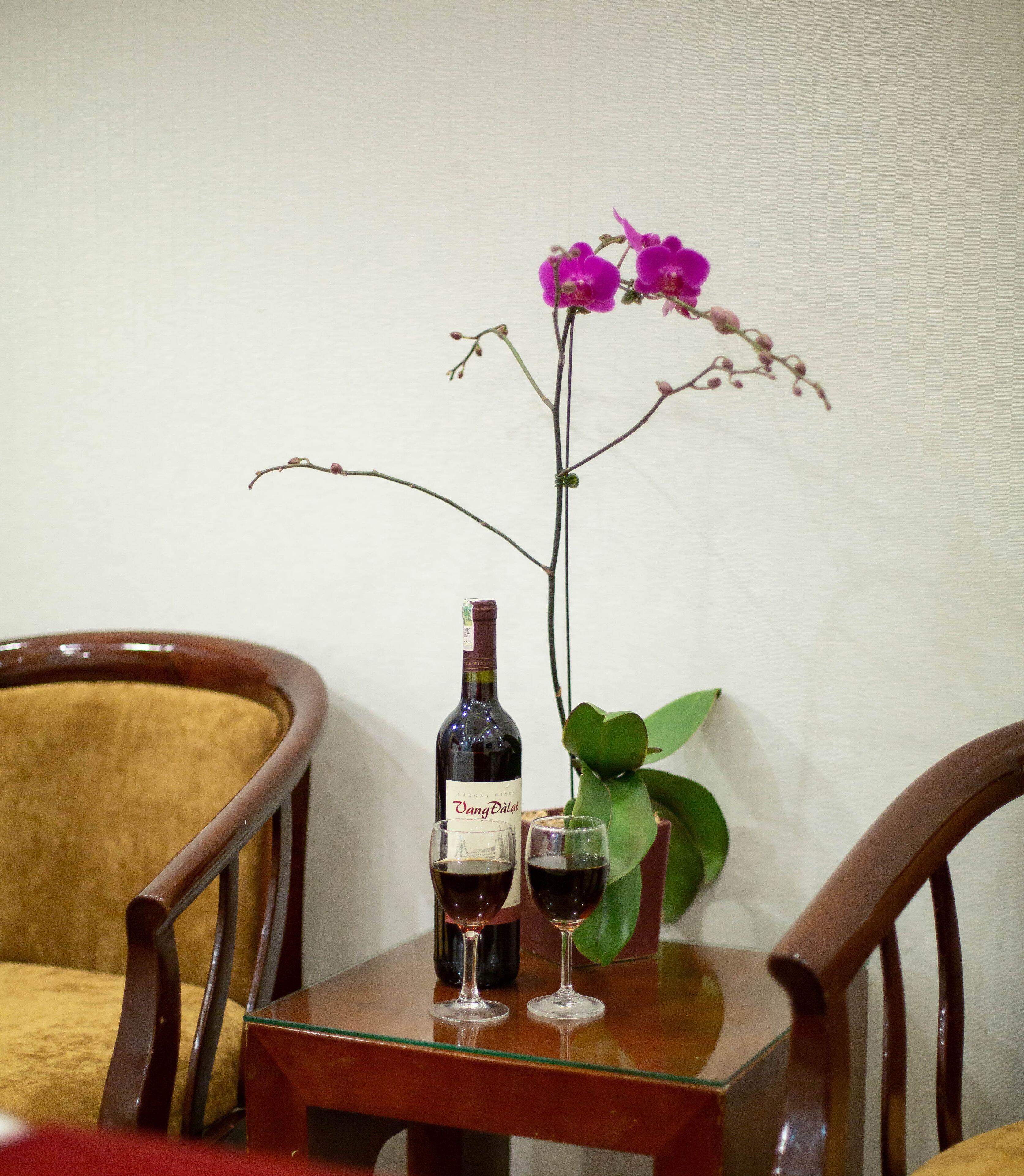 A table with a bottle of wine, two glasses, and a single orchid.