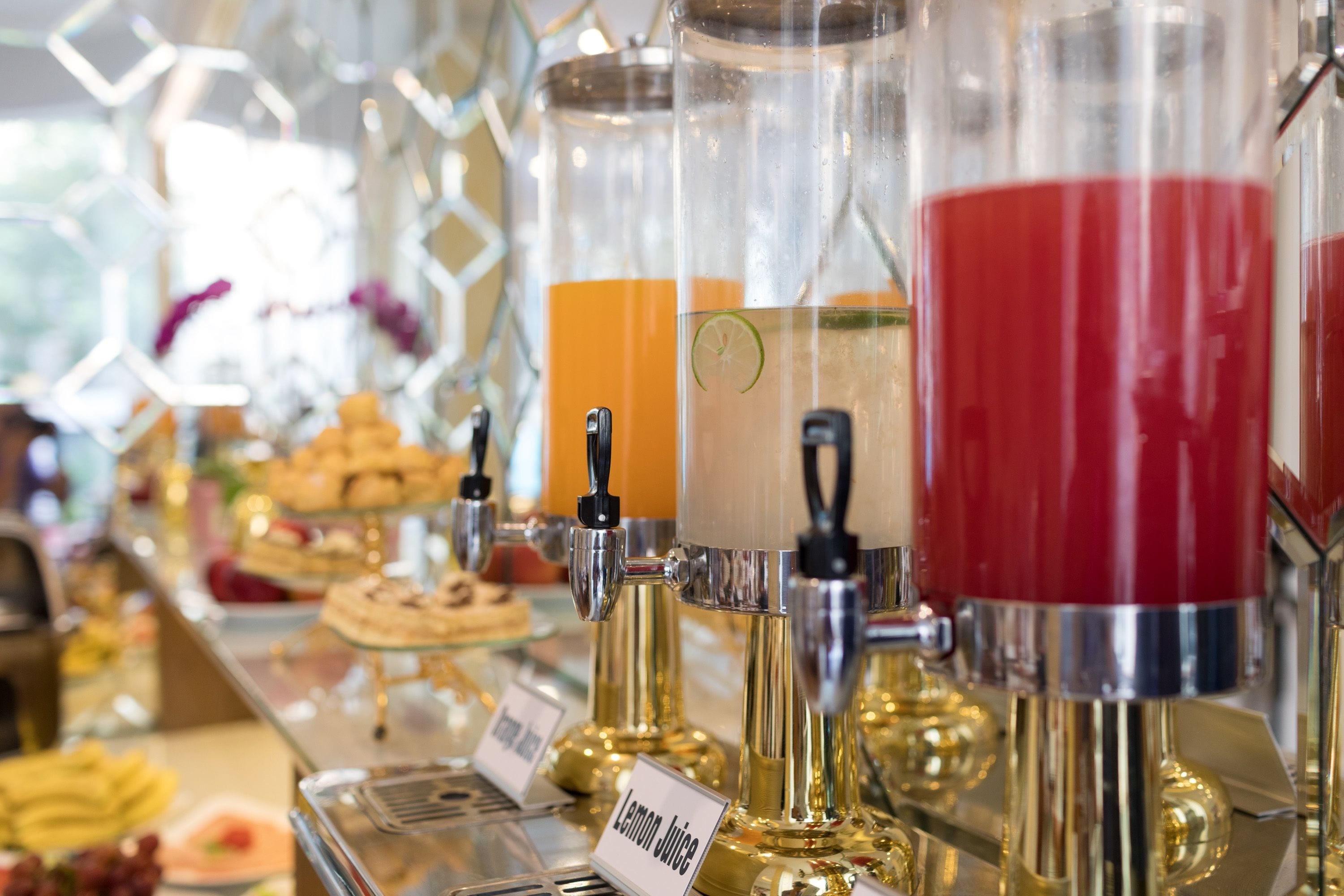 Ein Getränkeausgabebereich mit Spendern, die mit ‚Zitronensaft‘ und ‚Orangensaft‘ beschriftet sind.