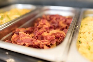 A buffet with various food items including bacon and scrambled eggs.