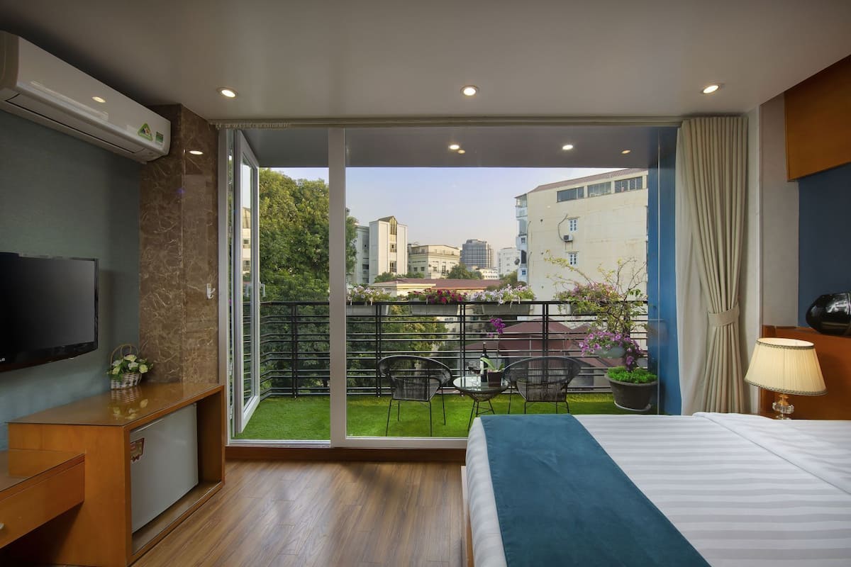 Une chambre d’hôtel avec un balcon, un lit, une télévision et un bureau.