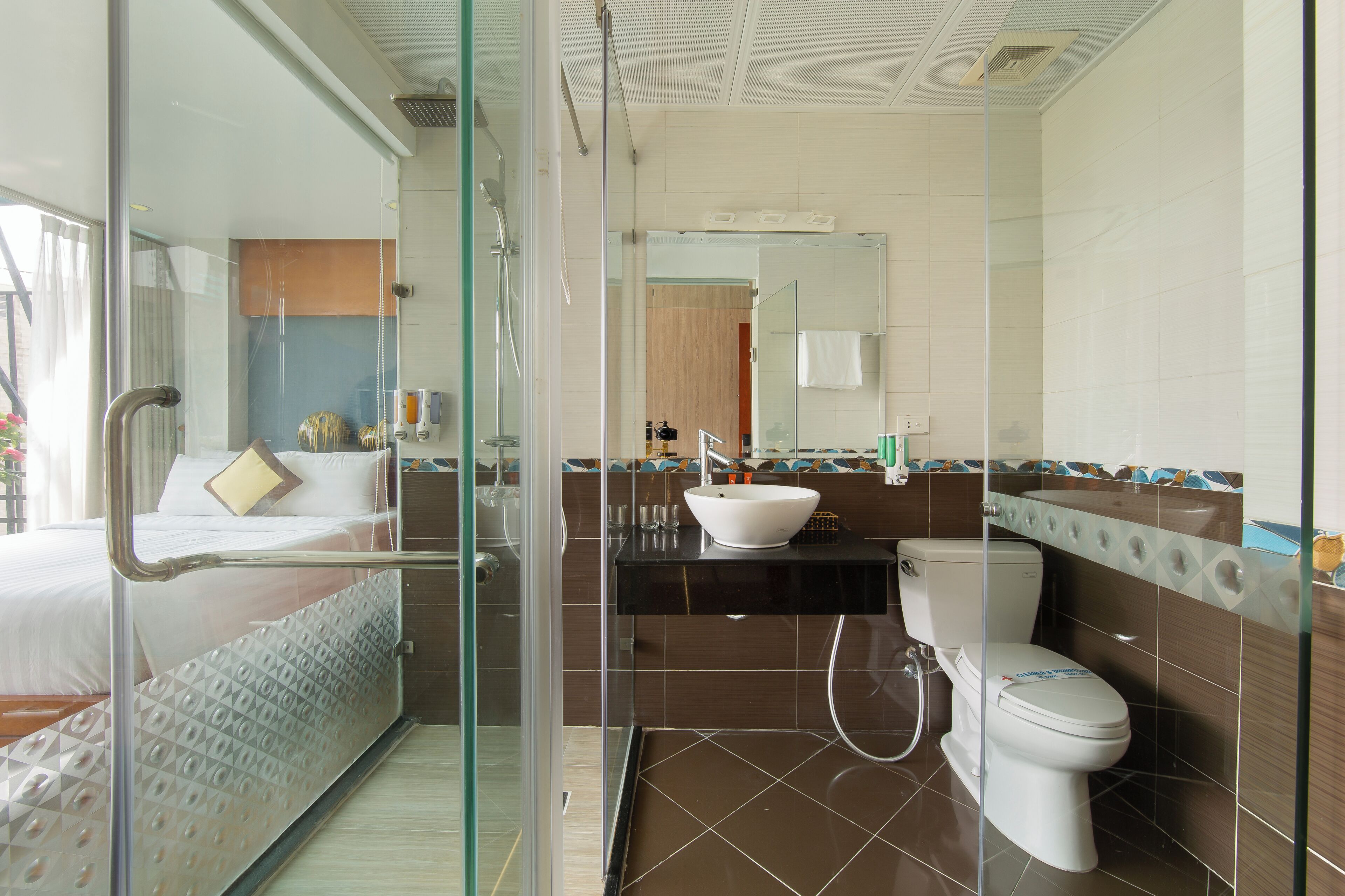Un baño de hotel con ducha envuelta en vidrio, un lavabo blanco y un inodoro.