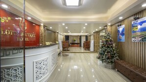 Un hall d’hôtel comprenant un comptoir d’accueil, un sapin de Noël et un espace salon.