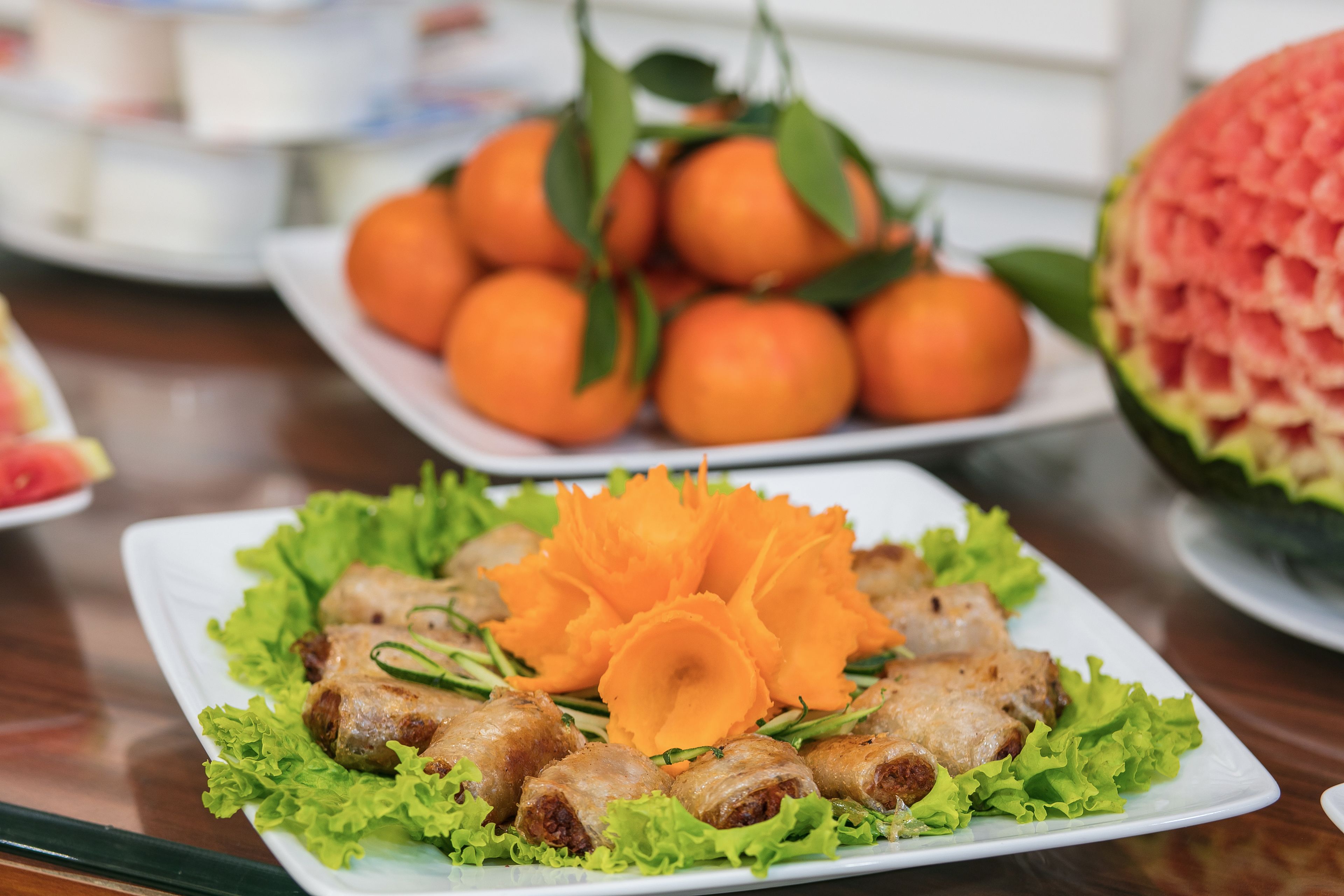 A table with a plate of food, a plate of oranges, and a carved watermelon.