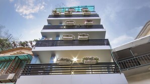 L’extérieur du Lotus Boutique Hotel présente un design moderne, avec une entrée imposante et un balcon agrémenté de plantes en pot.