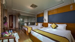 Une chambre d’hôtel avec deux lits, un coin salon avec une table et des chaises, et une vue sur la salle de bain et la cuisine.