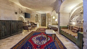 Une pièce avec un mur en pierre, un meuble en bois, un canapé, une table et un tapis à motifs.