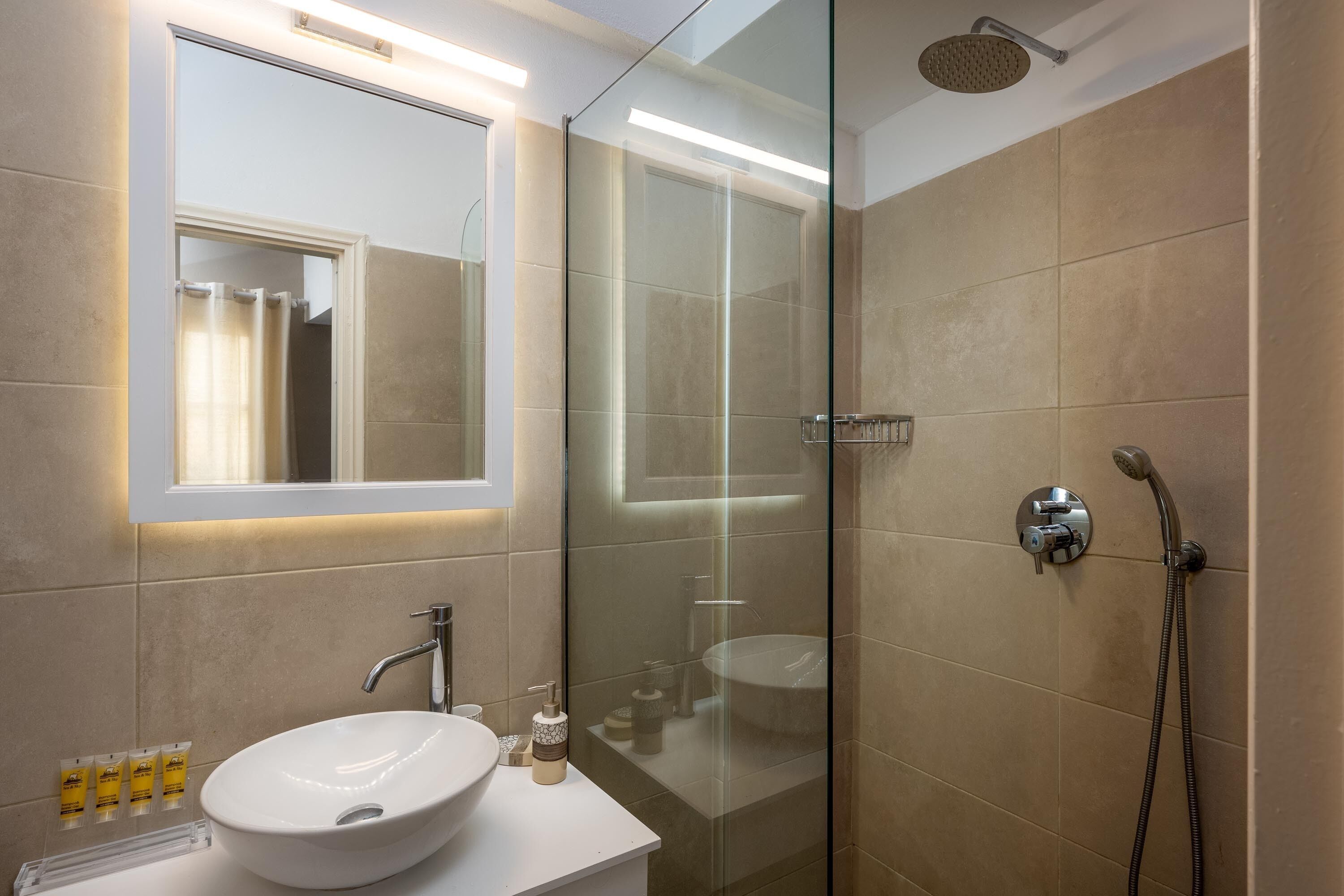 Un bagno moderno con doccia vetrata, lavandino bianco e specchio sopra.