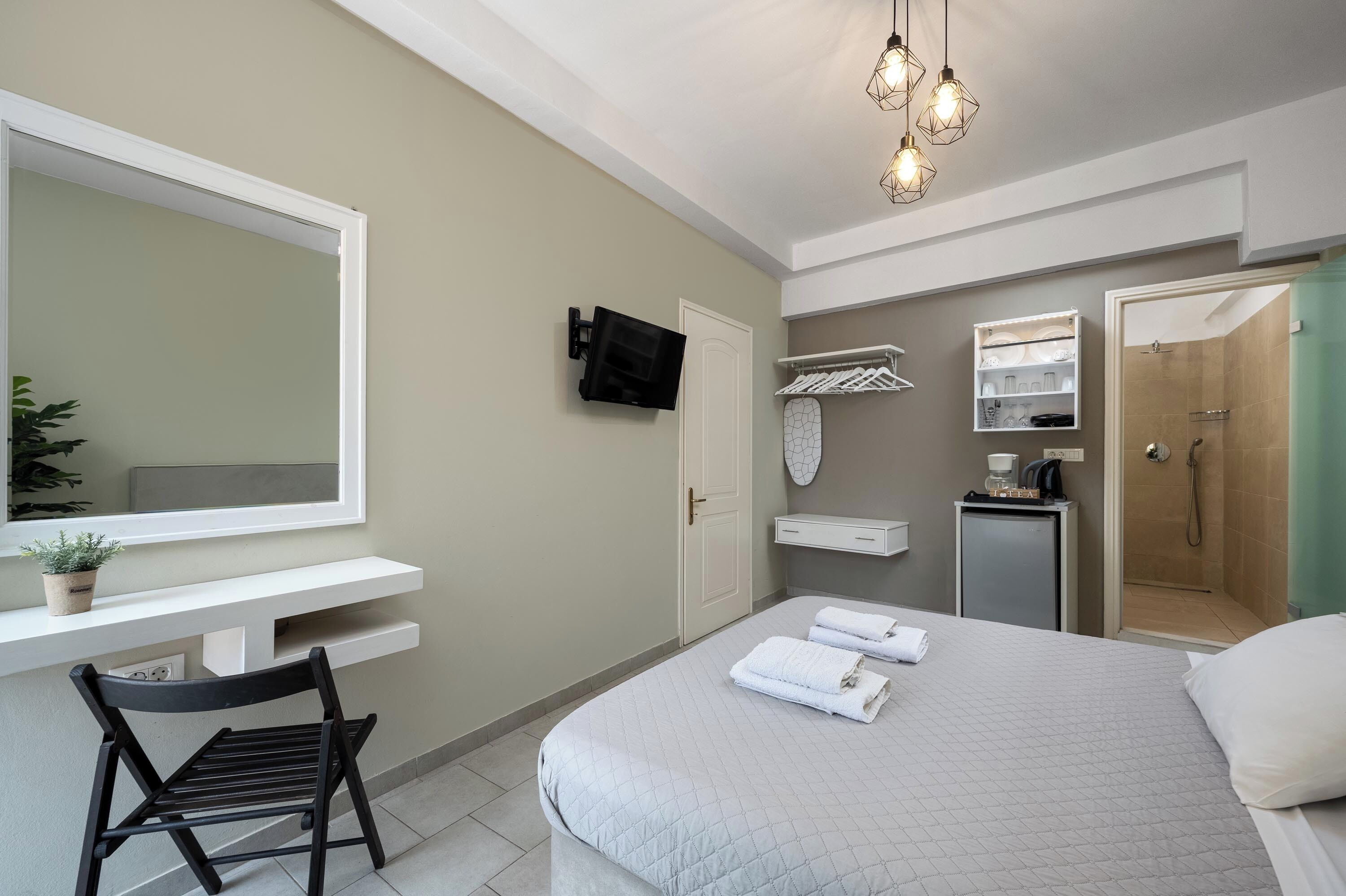 Une chambre d’hôtel moderne avec un grand lit, un bureau avec une chaise, une télévision, une douche et un petit placard.