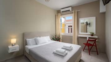 Un dormitorio ordenado con cama, mesita de noche y escritorio con silla.