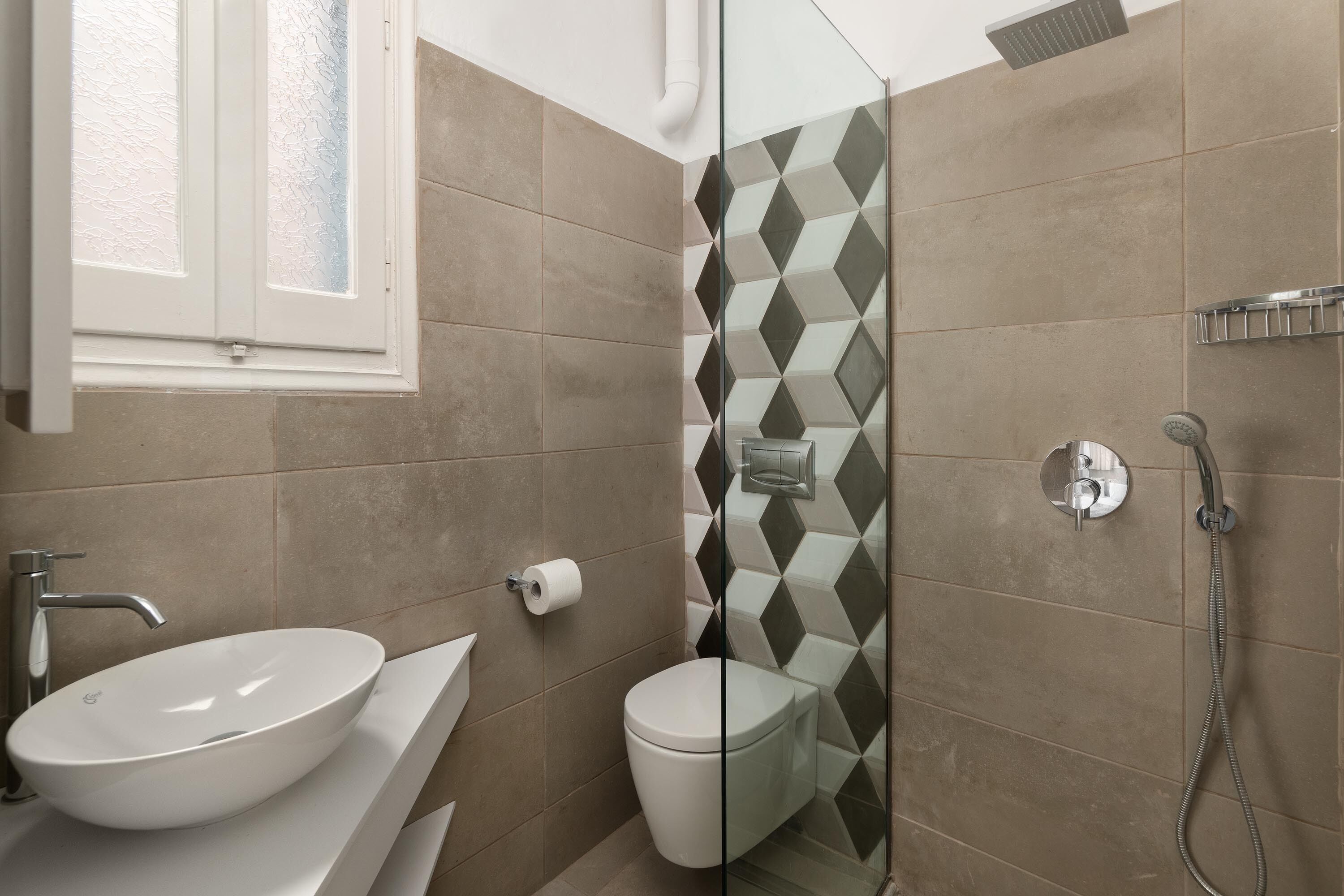 Un baño con lavamanos blanco, inodoro y zona de ducha.
