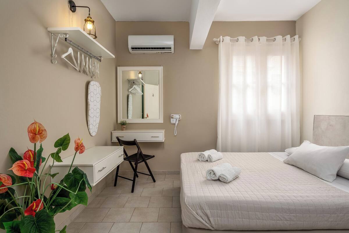 Quarto com cama, escrivaninha, cadeira, espelho e planta em vaso.