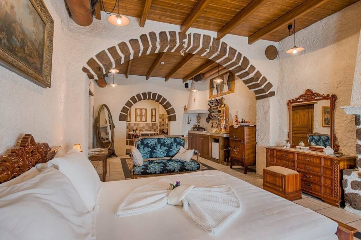 A bedroom with a bed, a blue floral sofa, a wooden dresser, and a mirror.